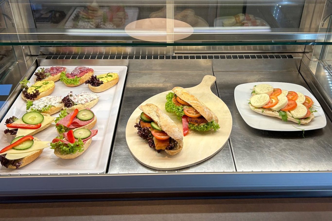 Auf dem Bild ist eine Vitrine zu sehen, in welcher diverse belegte Brötchen ausgestellt sind.